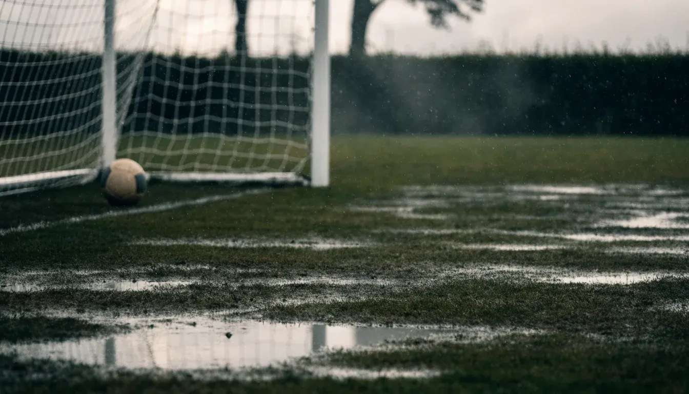 Ein Fußballtor mit Netz auf einem Trainingsplatz bei Regen, Pfützen stehen auf dem Rasen, niemand ist zu sehen.